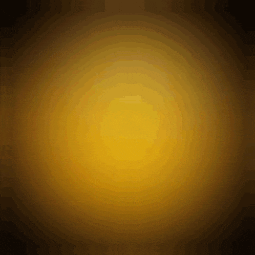 a yellow circle is glowing in the dark on a dark background .