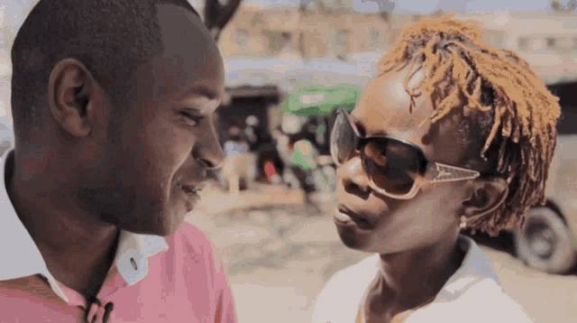 a man and a woman are looking into each other 's eyes and the woman is wearing sunglasses
