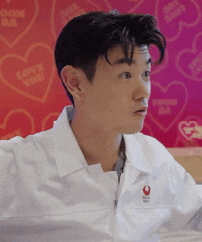 a man wearing a white shirt with a red heart that says love you on it