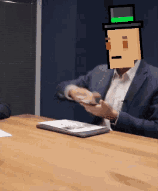 a man sitting at a table with a pixelated face on his head