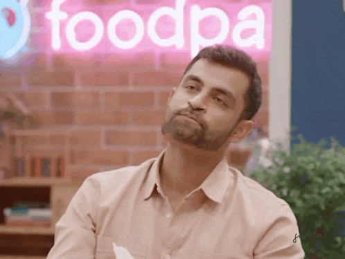 a man is sitting in front of a sign that says foodpa