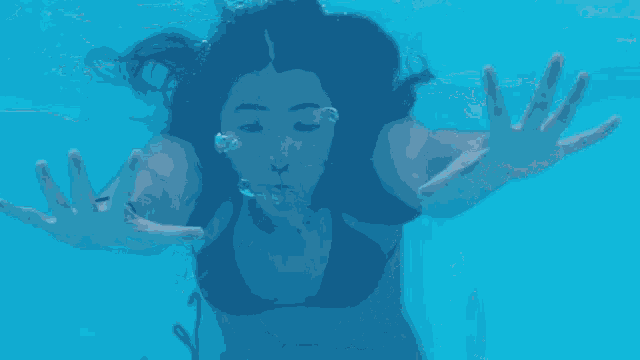 a woman in a bikini is swimming under water