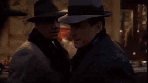 two men wearing hats are standing next to each other .