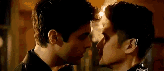 a couple of men are kissing each other on the forehead .