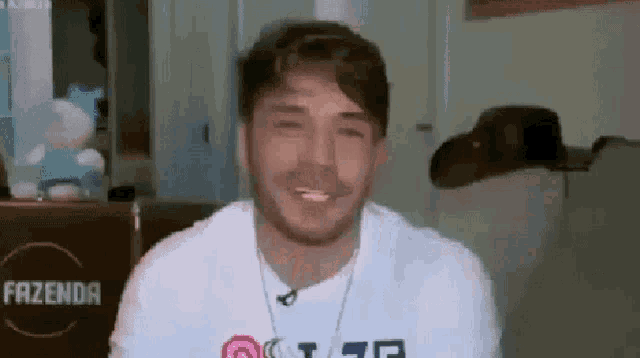 a man with a beard is wearing a white shirt and a necklace and smiling .