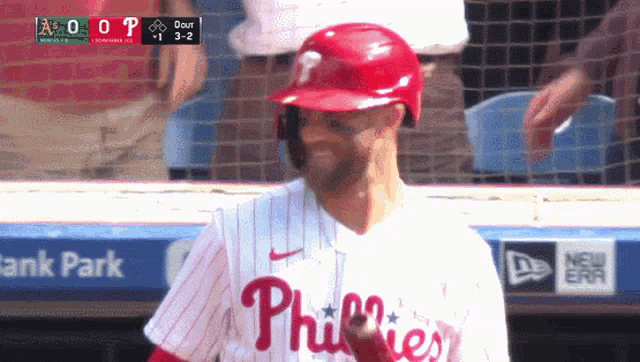 a baseball player wearing a phillies jersey stands in the dugout