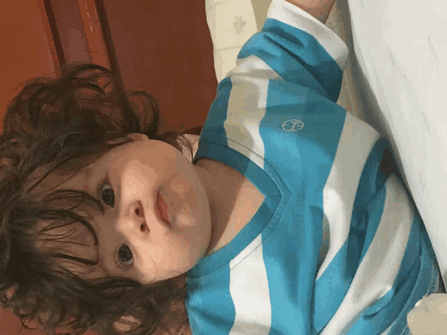 a little boy wearing a blue and white striped shirt with a mercedes logo