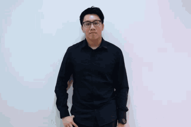 a man wearing a black shirt is covering his eyes with his hand .