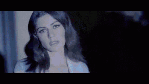a close up of a woman 's face in a dark room with a purple light behind her .