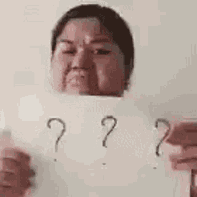 a woman is holding a piece of paper with question marks on it .