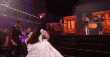 a woman in a white dress is dancing on a stage in front of a crowd of people .
