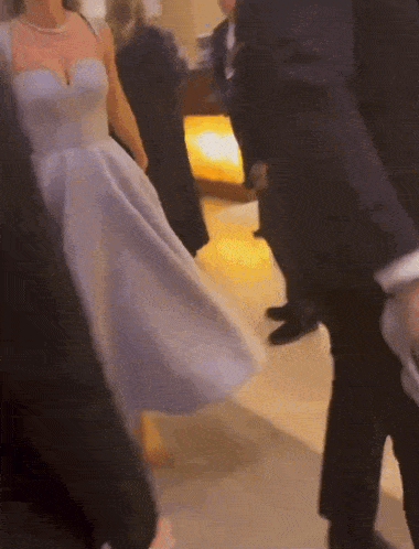 a woman in a white dress is walking down a hallway