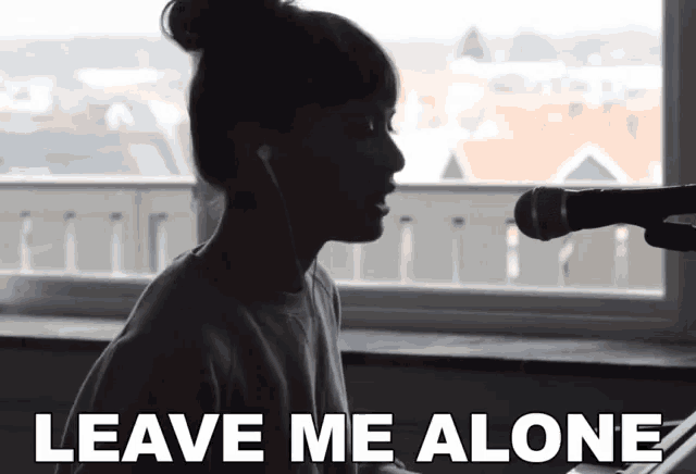 a woman singing into a microphone with the words " leave me alone " above her