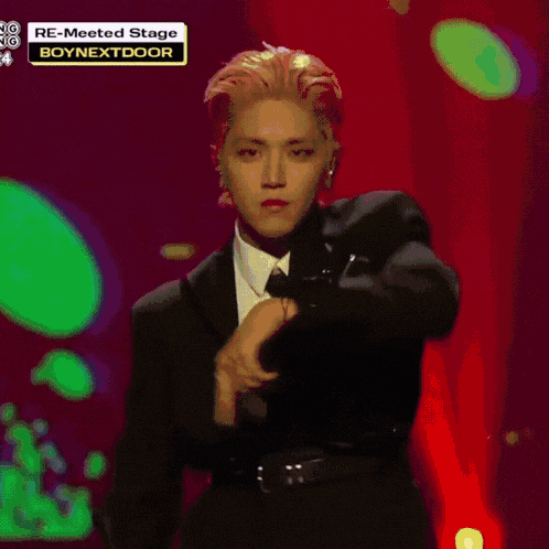 a man in a suit and tie is dancing on a stage that says boynextdoor on it