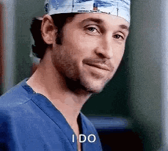 a close up of a man wearing a surgical cap and scrubs smiling .