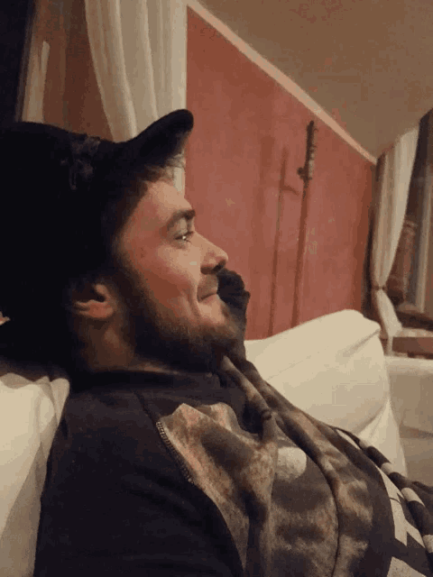 a man with a beard is laying on a couch with his eyes closed