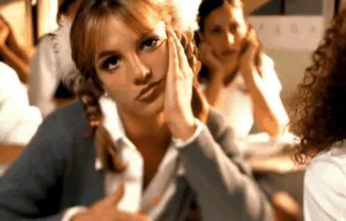britney spears is sitting at a table with her hand on her chin .