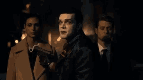 a man in a joker costume is holding a gun and smiling .