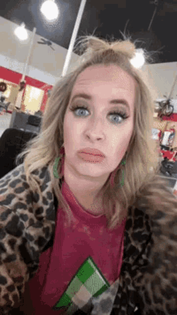 a woman wearing a leopard print jacket and a pink shirt is making a face