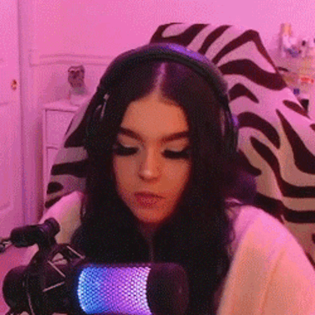 a woman wearing headphones and a microphone is sitting in front of a microphone .