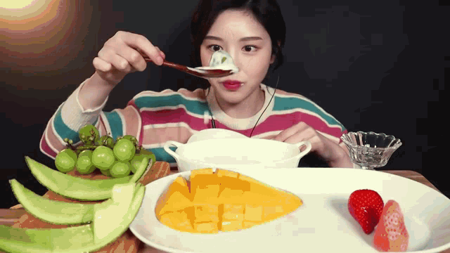 a woman is eating fruit with a spoon and a bowl