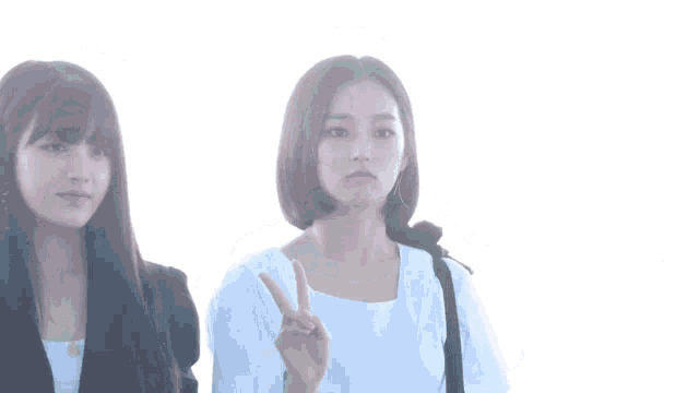 two young women are standing next to each other and one of them is giving a peace sign
