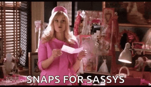 a woman in a pink dress is holding a piece of paper and says snaps for sassy .