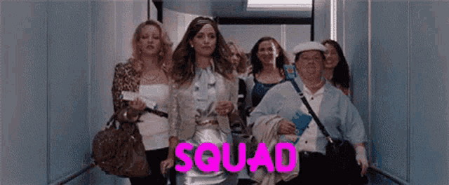 a group of women are walking down an elevator with the word squad written on the bottom .