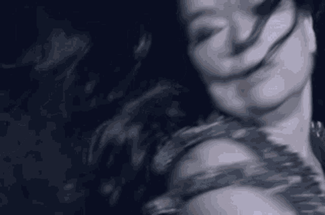 a close up of a woman 's face with her hair blowing in the wind in a dark room .