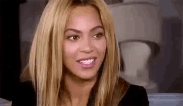 a close up of a woman 's face with blonde hair and a black jacket .