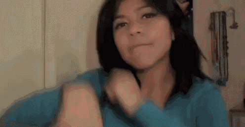a woman is wearing a blue sweater and making a face .