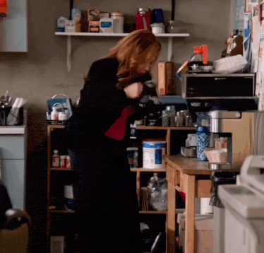 a woman standing in a kitchen with a keurig coffee maker on the counter