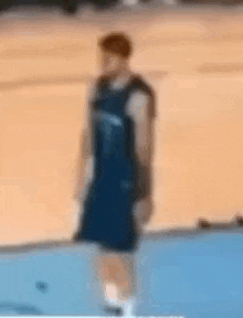 a basketball player in a blue jersey is standing on a basketball court .