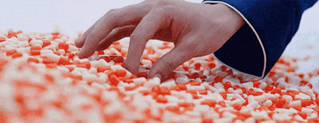 a person is touching a pile of red and white candy