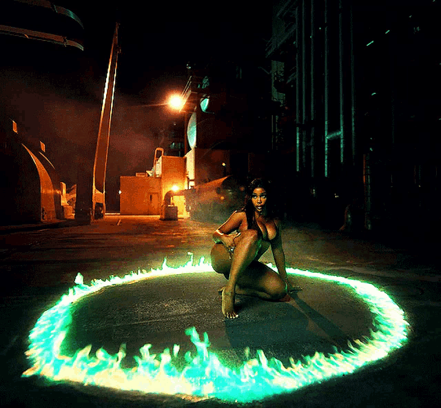 a woman is kneeling in a circle of green flames