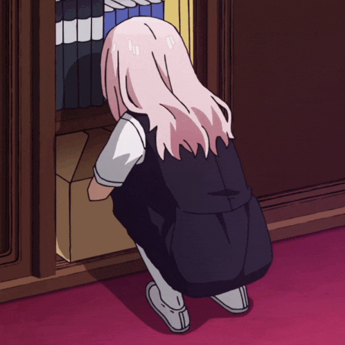 a girl with pink hair is kneeling down in front of a bookcase