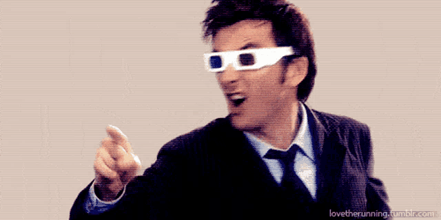 a man in a suit and tie wearing 3d glasses points his finger