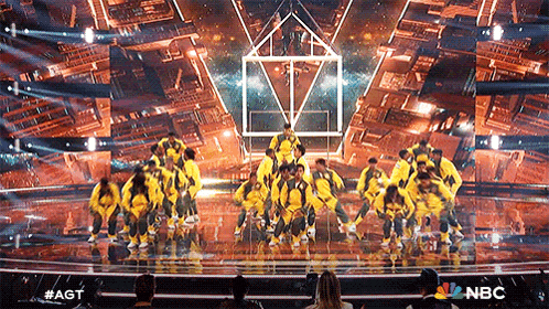 a group of people are dancing on a stage with the nbc logo in the background