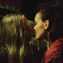 two women are kissing in front of a sign that says ' 12 club '