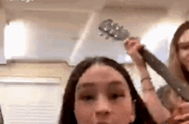 a woman is holding a guitar over her head while another woman plays a guitar .
