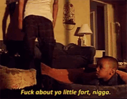 a man is standing next to a little boy who is laying on a couch and says " fuck about yo little fort nigga "