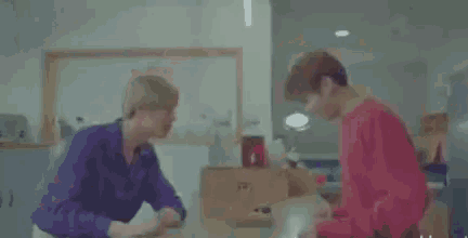 two men are standing next to each other in a kitchen and talking to each other .