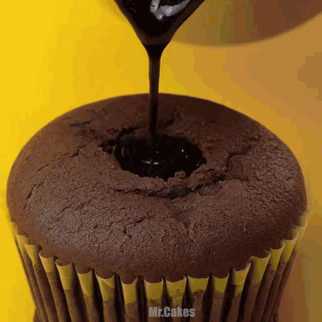 a chocolate cupcake with a hole in the middle is being drizzled with chocolate sauce