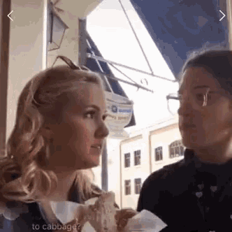 two women are talking to each other while one of them is holding a piece of bread .