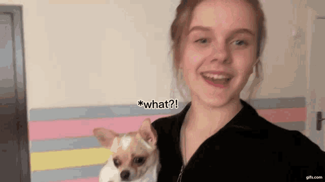 a girl is holding a small dog and says " what " at the bottom