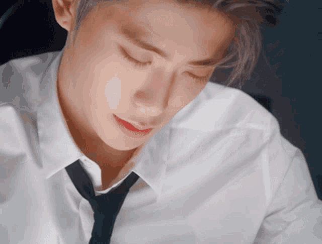 a man wearing a white shirt and tie is looking down