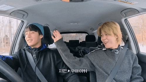 two men are sitting in a car and one of them is wearing a hat