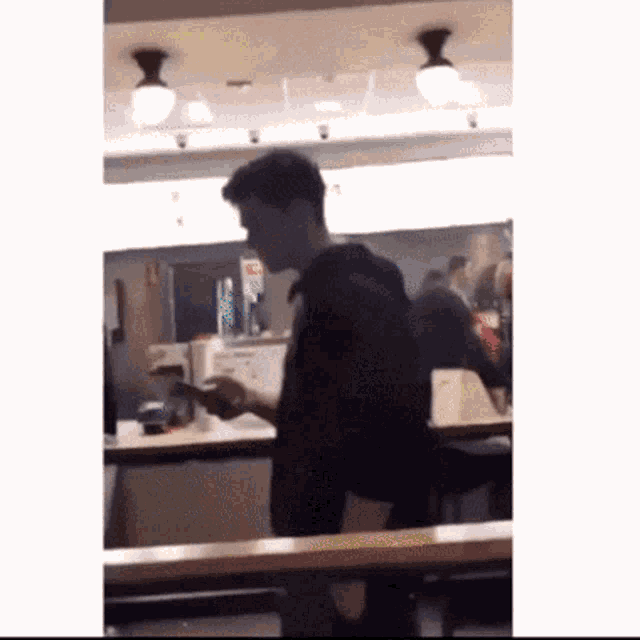 a man in a black shirt is looking at his phone