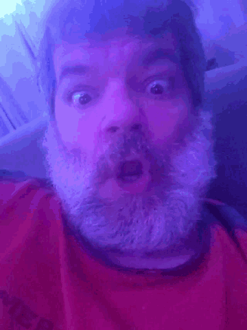 a man with a beard is laying on his back in a blue light