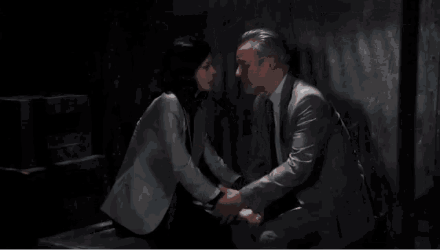 a man and a woman are kissing in a dark room .